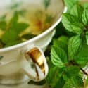 A cup of peppermint tea with peppermint leaves